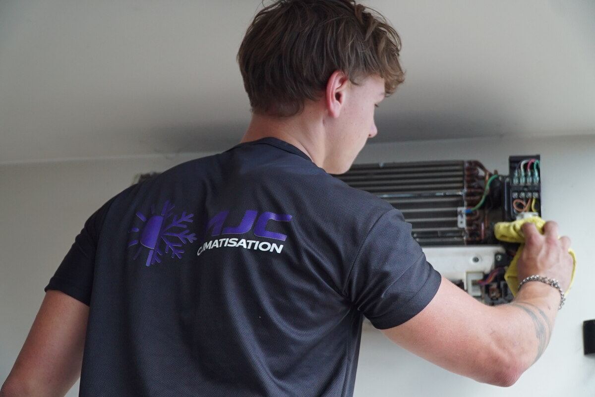Technicien MJC Climatisation vu de dos, en intervention sur le circuit électrique d'une climatisation